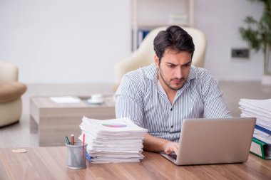 Young employee and too much work at workplace