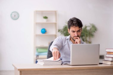 Genç erkek öğrenci işyerinde oturuyor.