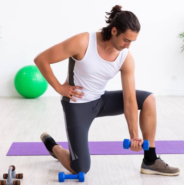 Genç yakışıklı adam içeride spor egzersizleri yapıyor.