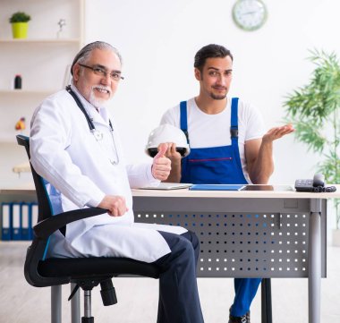 Genç erkek müteahhit yaşlı doktoru ziyaret ediyor.