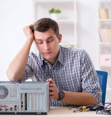 Atölyede bilgisayar tamir eden genç teknisyen