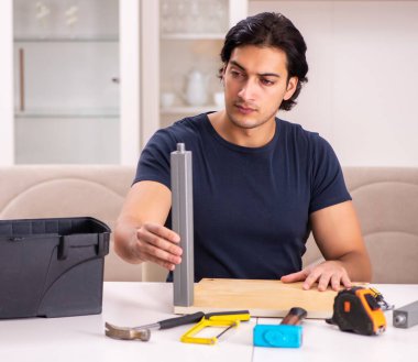 Evde mobilya tamir eden genç adam.