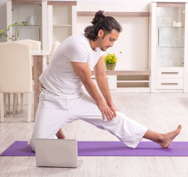 Genç adam evde fiziksel egzersiz yapıyor.