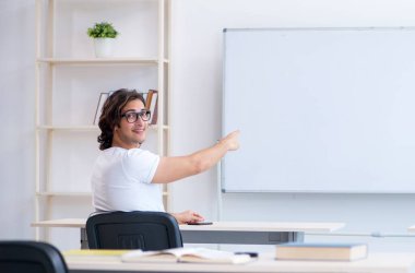 Beyaz tahtanın önündeki genç erkek öğrenci.