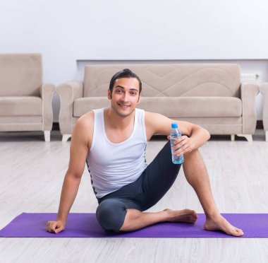 Genç adam evde antrenman ve egzersiz yapıyor.