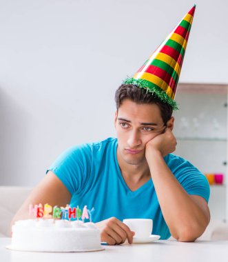 Doğum gününü evde yalnız kutlayan genç adam.