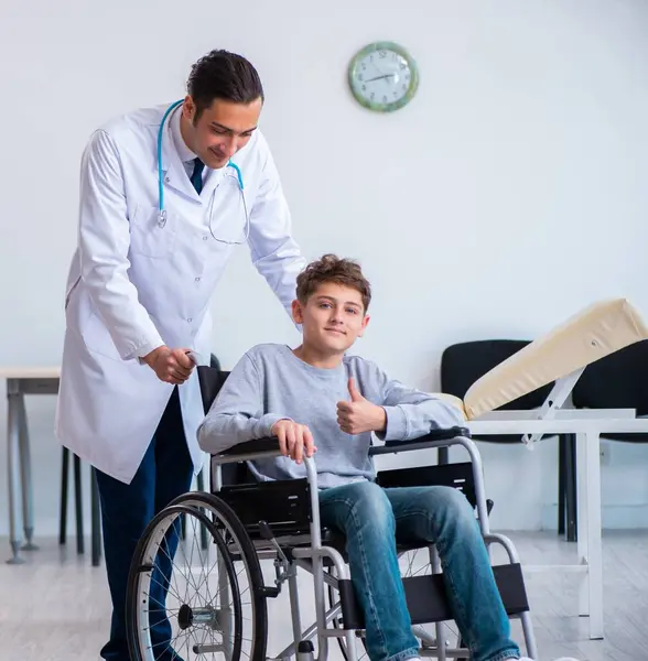 若い男性医師小児科医と車椅子の少年 — ストック写真