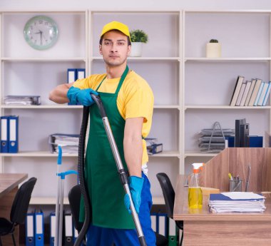 Genç erkek müteahhit ofisi temizliyor.