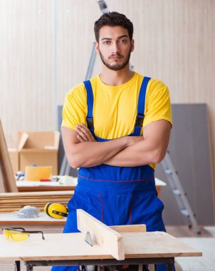 Genç tamirci marangoz dairesel testereyle odun kesiyor.