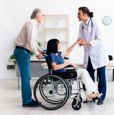 Yaşlı çift genç erkek doktoru ziyaret ediyor.