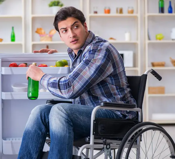 The young disabled injured man opening the fridge door