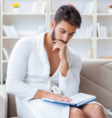 Öğrenci işadamı genç adam evde çalışarak kitap okuyor.