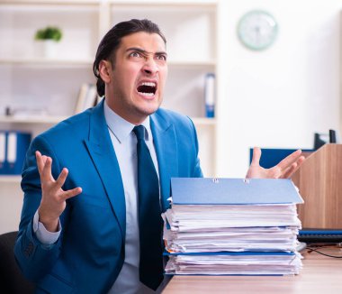 Genç yakışıklı işadamı ofiste oturuyor.