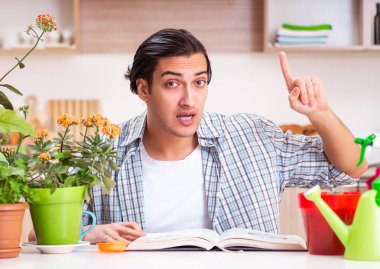 Genç yakışıklı adam evde çiçek yetiştiriyor.