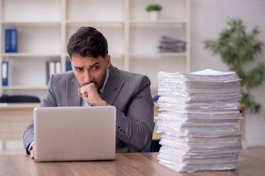 Young employee and too much work at workplace