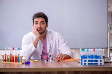Young chemistry teacher sitting in the classroom