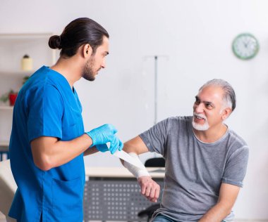 Genç erkek doktor ve yaşlı hasta ilk yardımda.