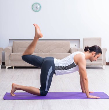 Genç adam evde antrenman ve egzersiz yapıyor.