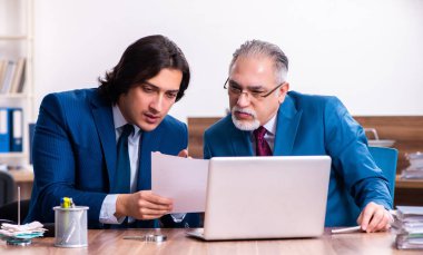 Genç ve yaşlı çalışanlar ofiste birlikte çalışıyorlar.