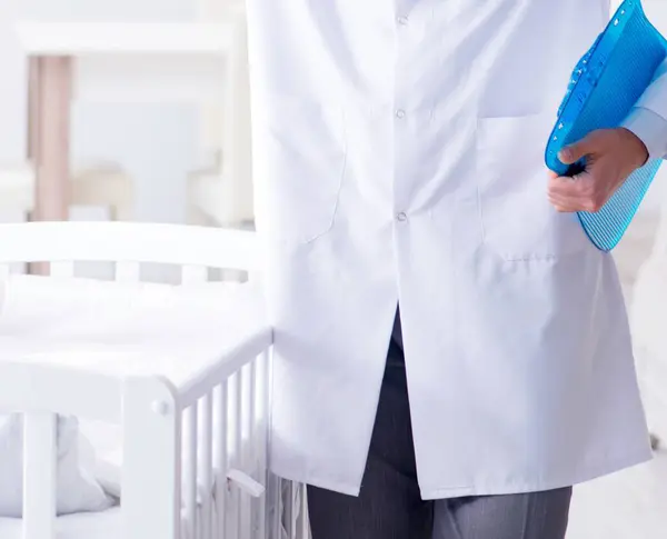 赤ん坊のベッドの近くの男性小児科医検査の準備 — ストック写真