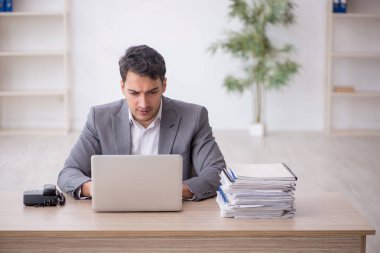 Young employee and too much work at workplace