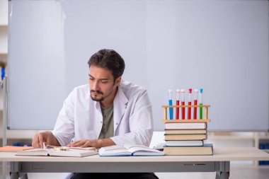 Genç kimyacı öğretmen beyaz tahtanın önünde.