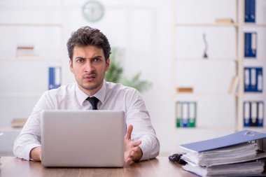 Young employee and too much work at workplace