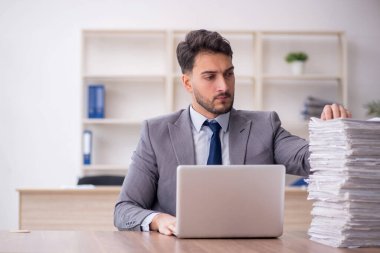 Young employee and too much work at workplace