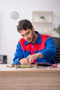 Laboratuvarda bilgisayar tamir eden genç bir tamirci.