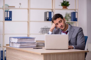 Genç işadamı işyerinde oturuyor.