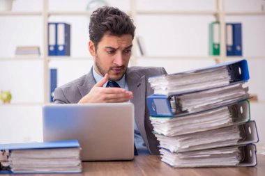 Young employee and too much work at workplace