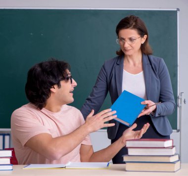 Sınıftaki yaşlı bayan öğretmen ve erkek öğrenci.