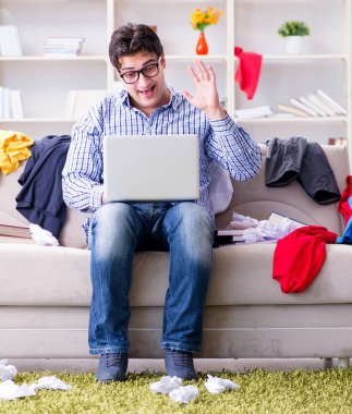 Dağınık odada çalışan genç adam.