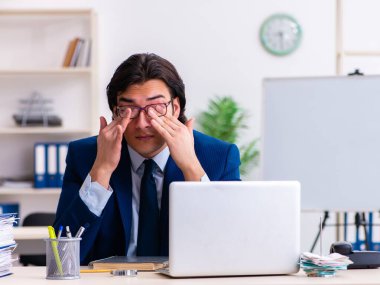 Genç işadamı ofiste oturuyor ve çalışıyor.