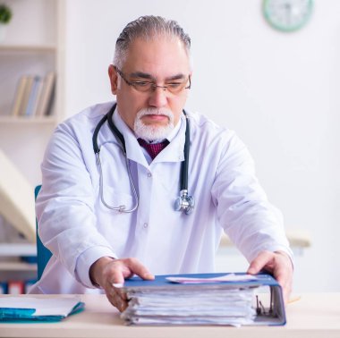 Klinikte çalışan yaşlı erkek doktor.