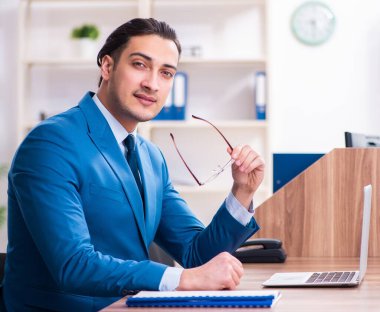 Genç yakışıklı işadamı ofiste oturuyor.