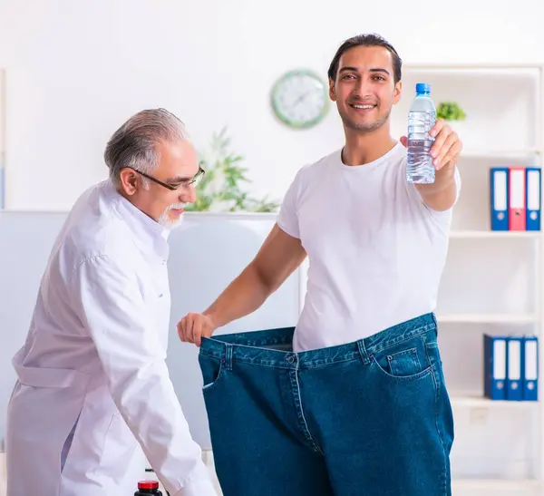 医者の栄養士と幸せな患者は大きなズボンを着て — ストック写真