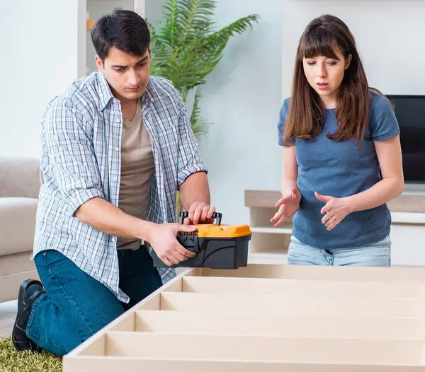 The young family assembling furniture at new house