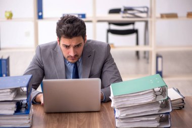 Young employee and too much work at workplace