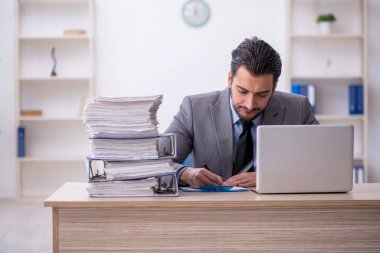 Genç bir çalışan ve ofiste çok fazla iş var.