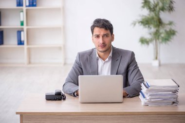 Young employee and too much work at workplace