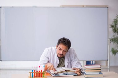 Genç kimyacı öğretmen beyaz tahtanın önünde.