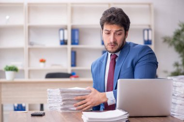 Young employee and too much work at workplace
