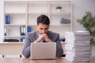 Young employee and too much work at workplace