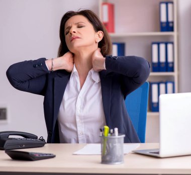 Ofiste acı çeken orta yaşlı kadın çalışan.