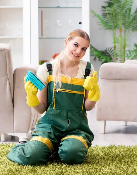 The professional female cleaner cleaning carpet