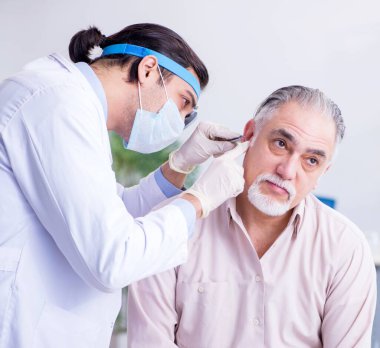 Erkek hasta doktor otolaringolojisti ziyaret ediyor.