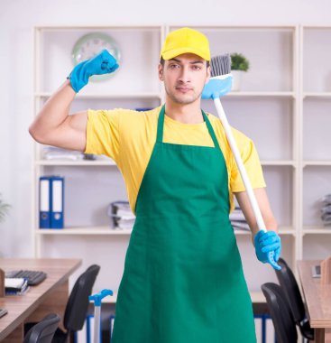 Genç erkek müteahhit ofisi temizliyor.