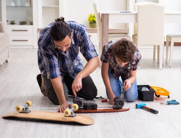 Young Father Repairing Skateboard His Son Home — Stock Photo, Image