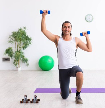 Genç yakışıklı adam içeride spor egzersizleri yapıyor.